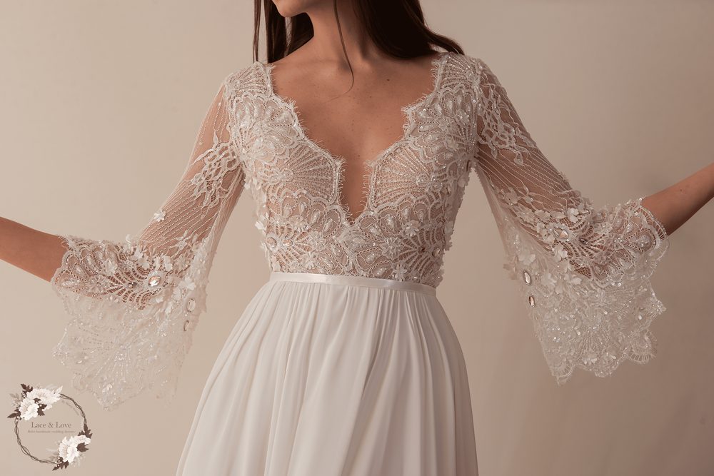 Wedding dress in beaded lace with three-quarter sleeves, the beading catching the light on the bodice.