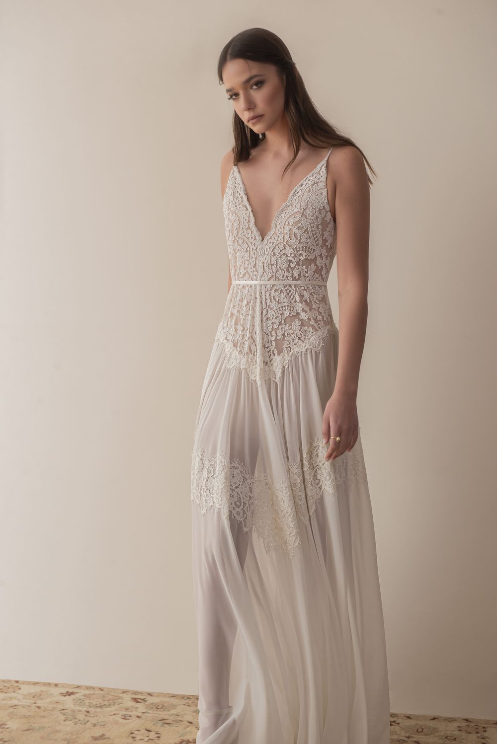 Bride in a soft boho wedding dress: French lace bodice with a deep V neckline over a flowing chiffon skirt, satin sash at the natural waist, open back.