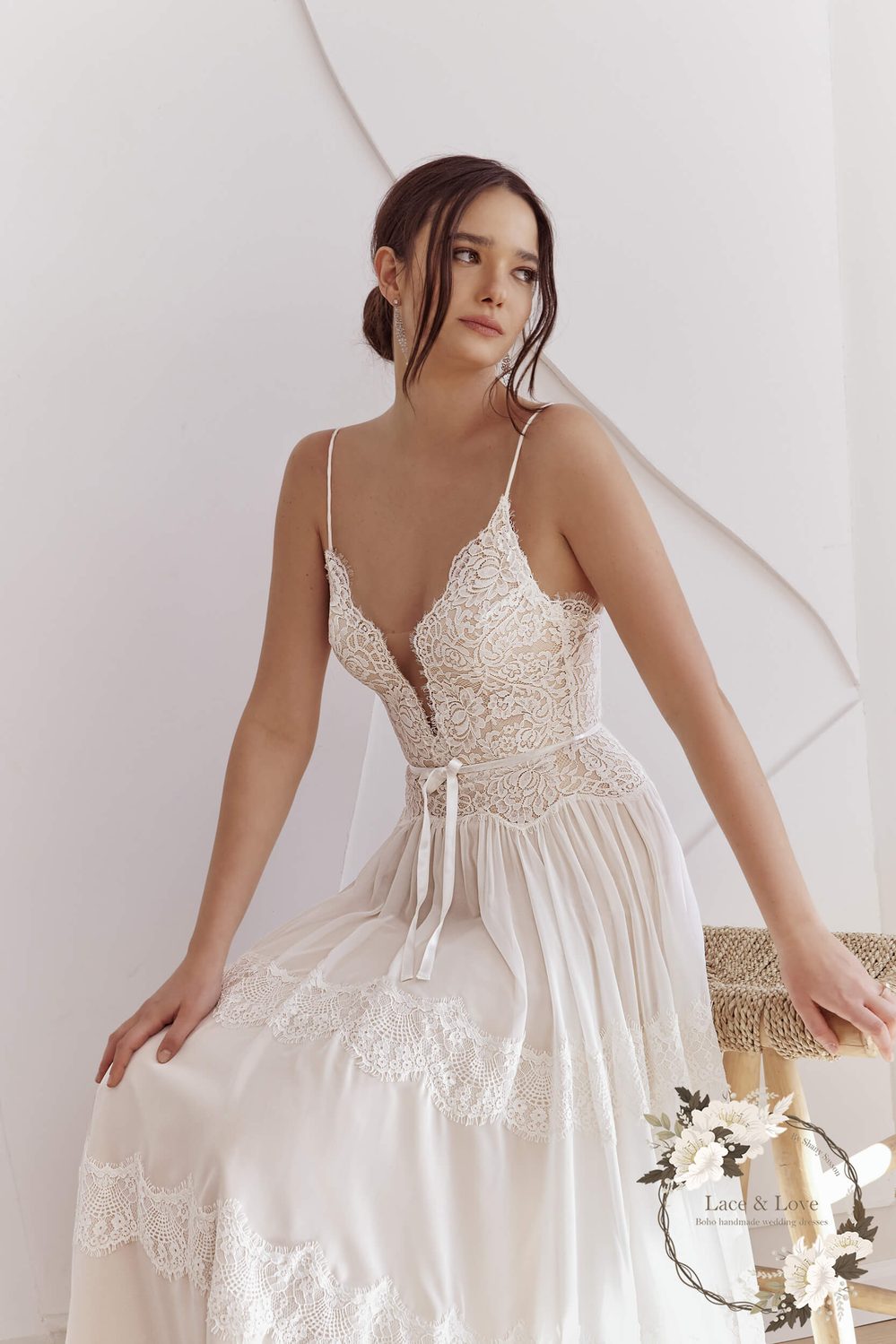 Seated bride in a wedding dress with a vintage lace bodice and a chiffon skirt spread around her.