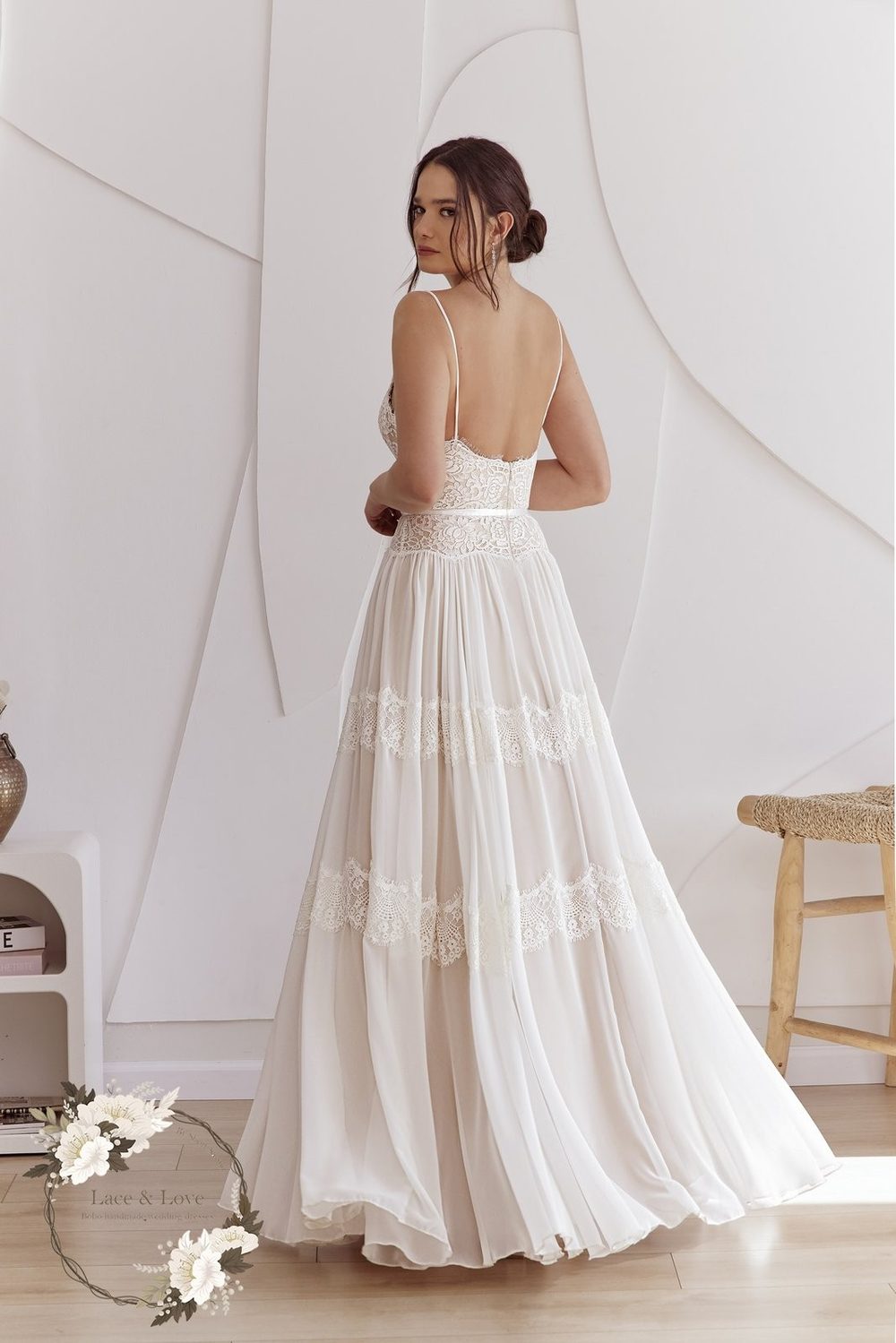 Back view of a bride in a lace wedding dress with an open back cut to the waist and a chiffon skirt.